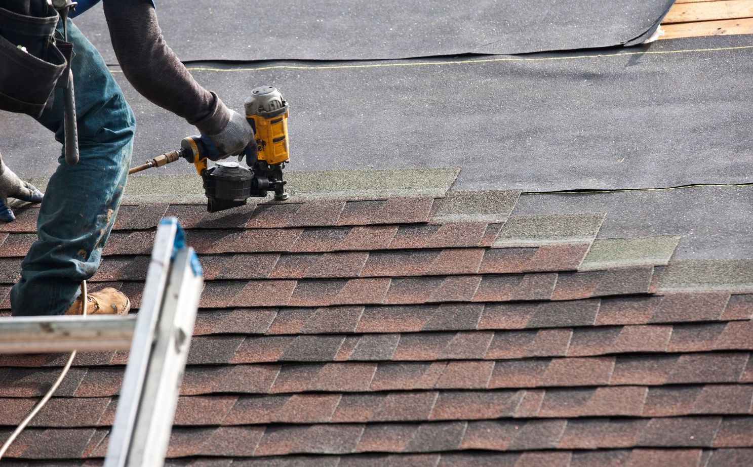 Worker adding shingles to roof