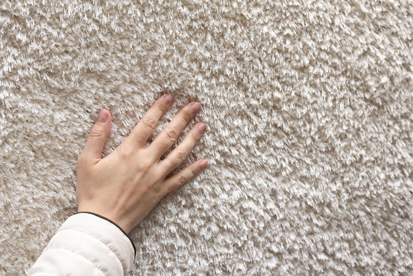 A hand touching carpet